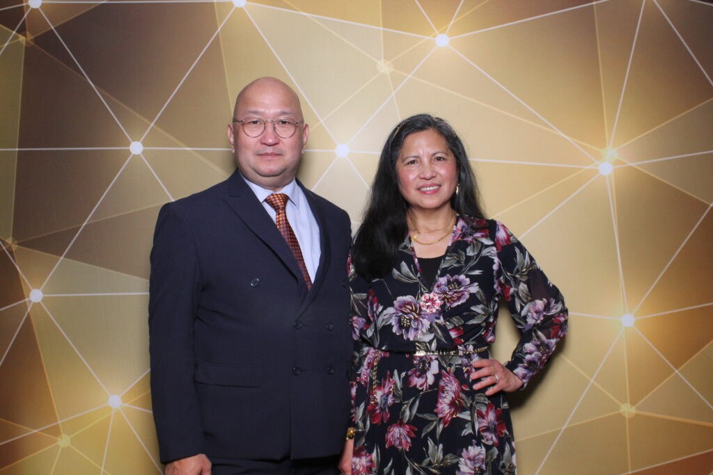 At Gala 2023 a man and woman pose together against a shimmering gold background in California