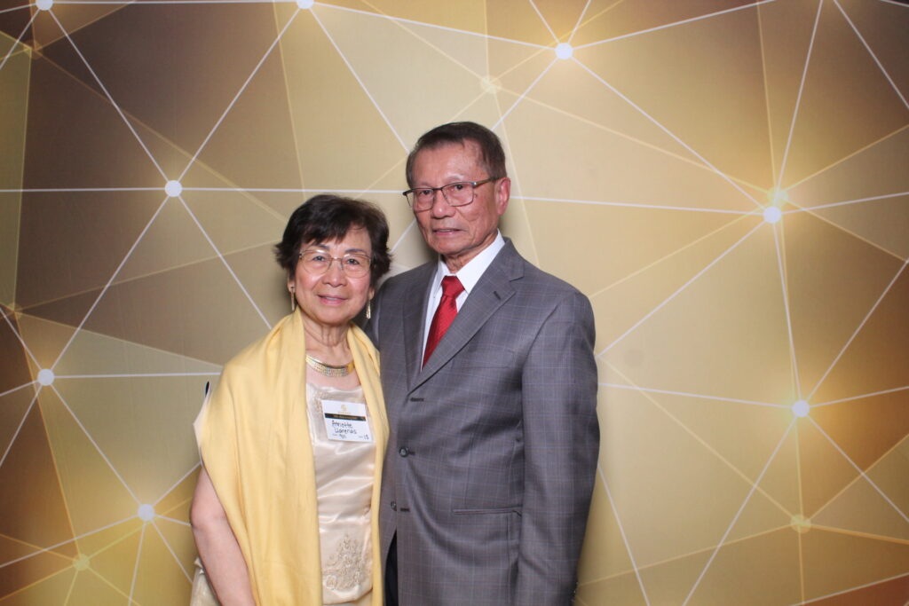 Asian man and woman pose together in front of a gold wall at Gala 2023 in California