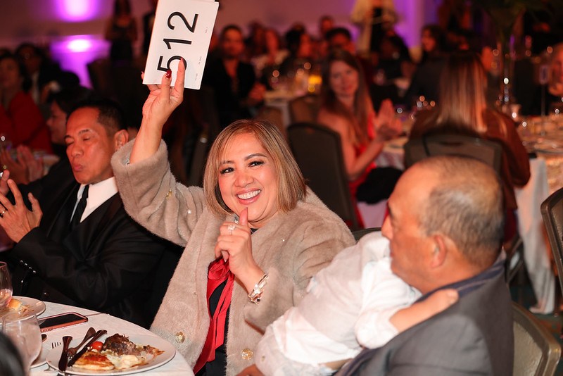 At a California dinner table, a woman displays numbers for Gala 2024