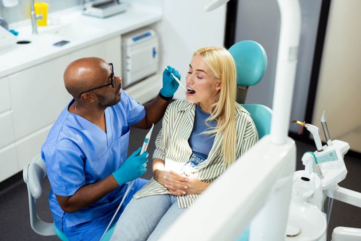 Dentist examining patient's teeth during checkup at clinic in San Diego, CA