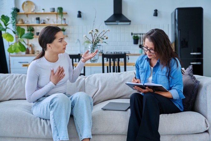 Therapist having a supportive psychotherapy session with a patient on a couch in San Diego, CA