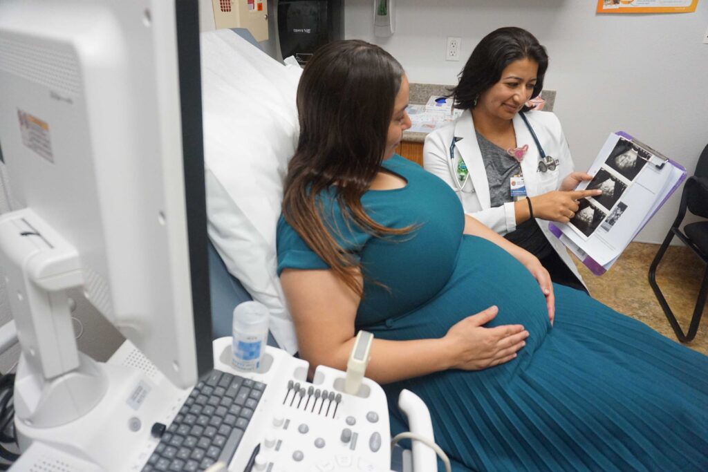 Patient reviewing printed ultrasound images with a healthcare provider in an exam room