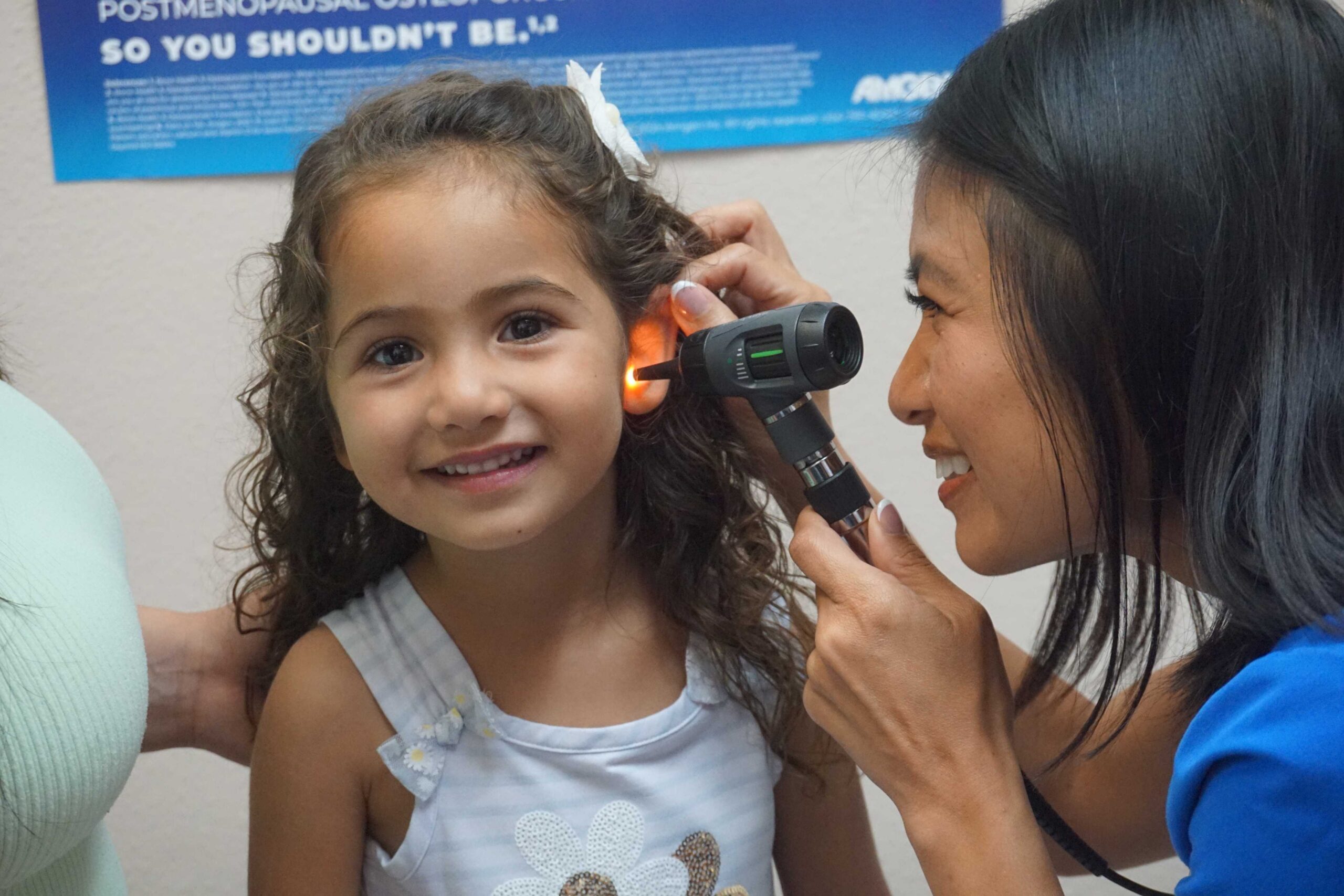 Healthcare professional examining a child's ear with an otoscope in a clinic room